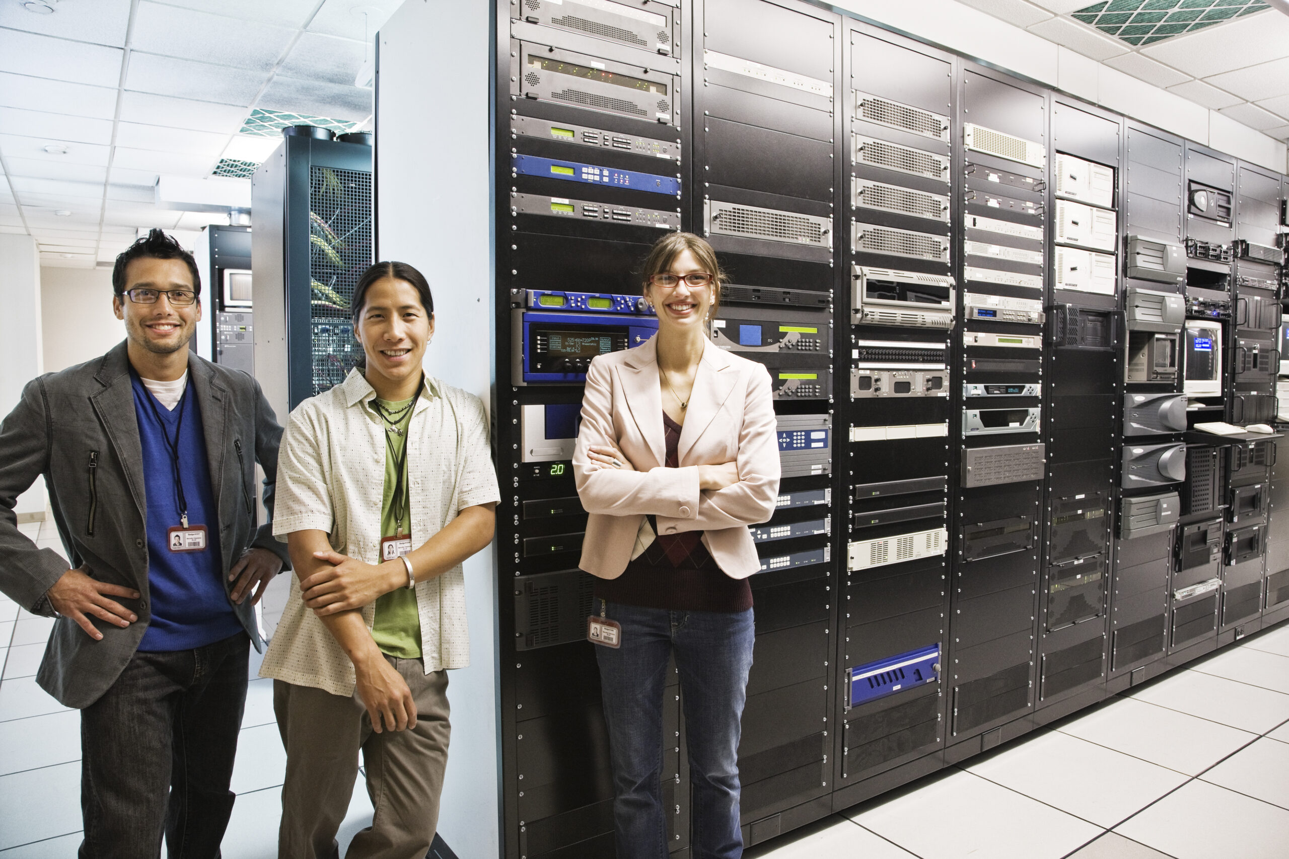 Portriat of three muli-ethnic technicians who work in a large computer server room.