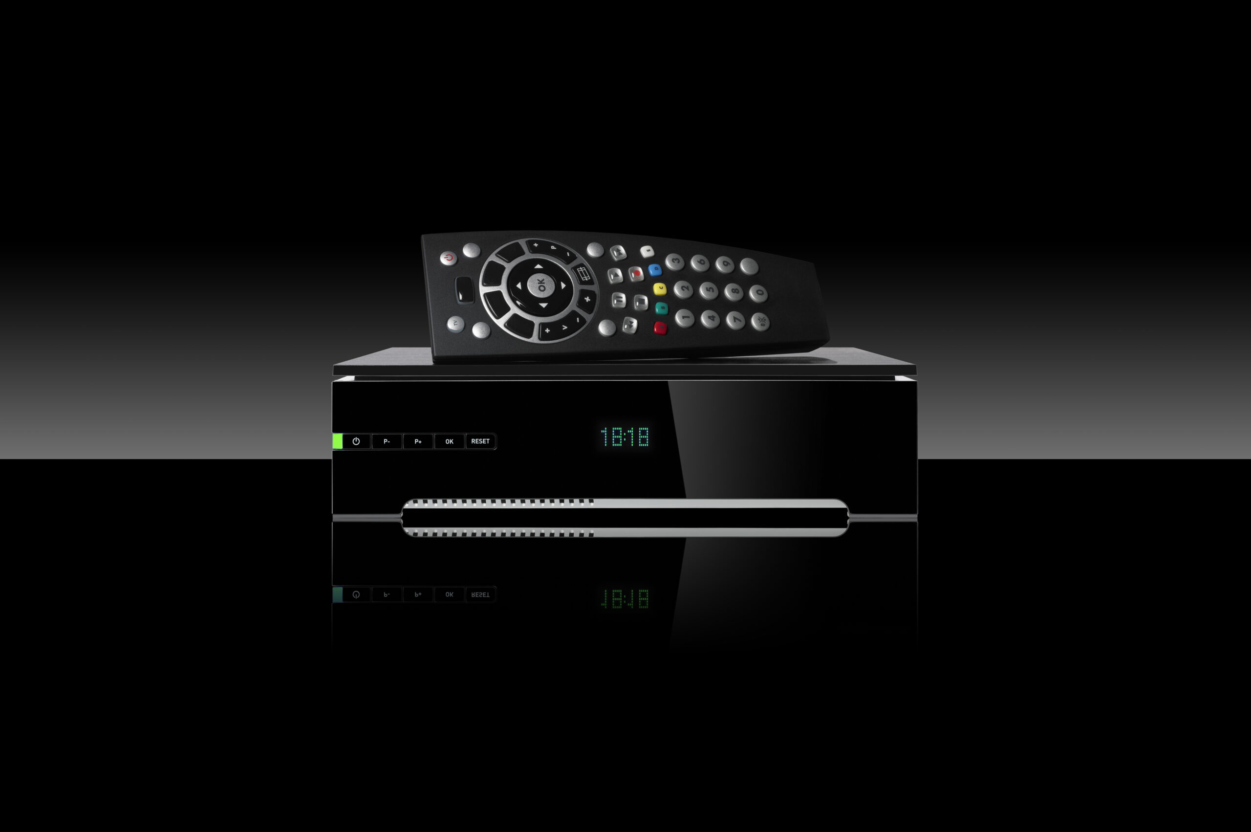 Tv decoder and remote control set on black background.